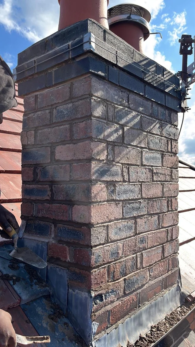 Brick chimney stack with metal flashing and a capped pot