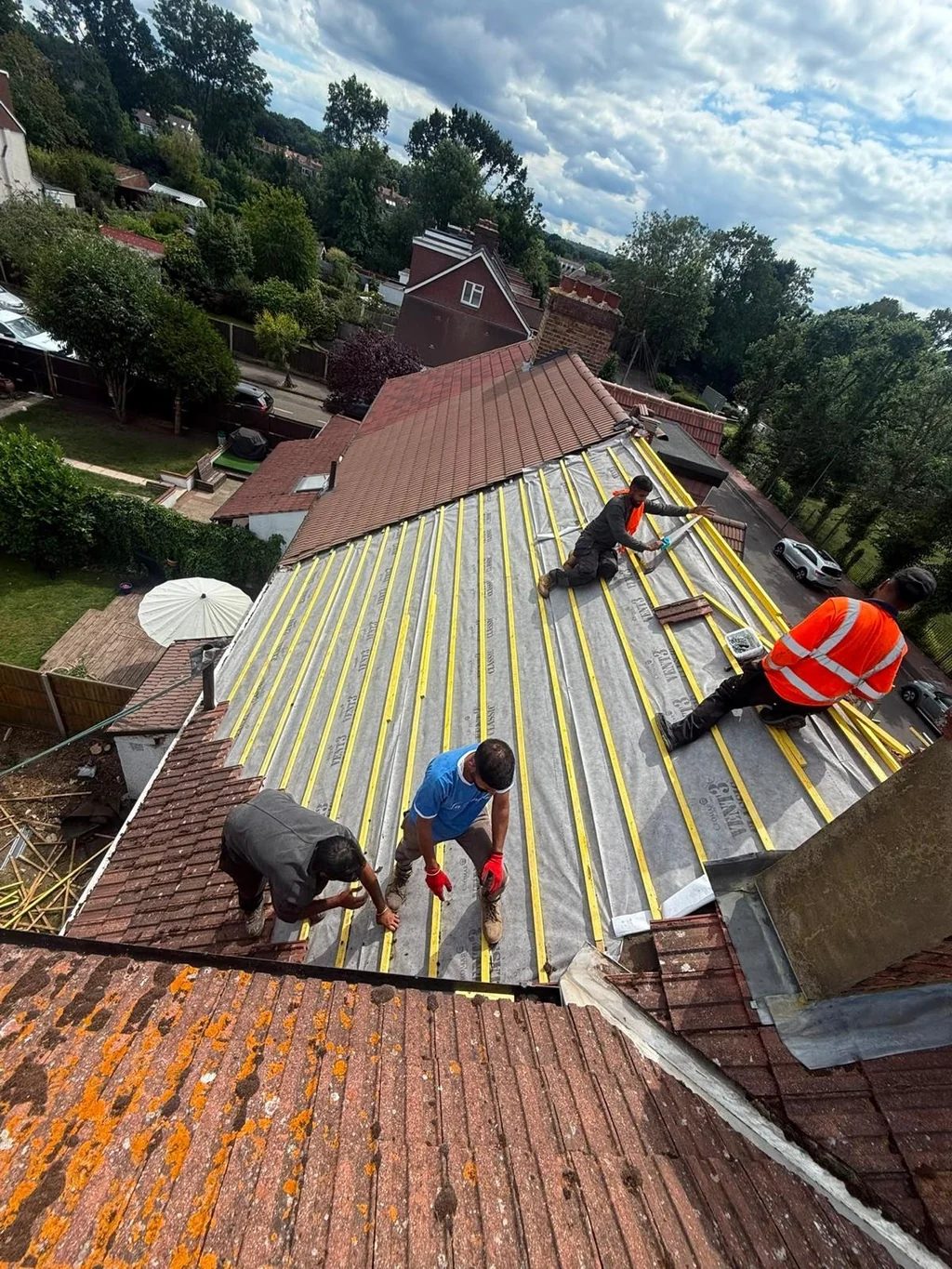 Four roofers fixing battens across roof membrane